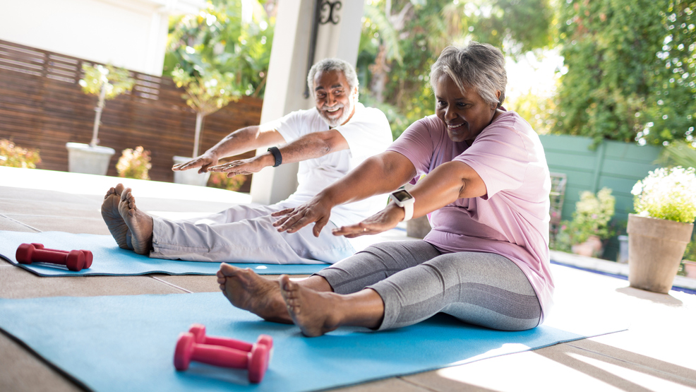 Full length of senior stretching exercise on mat in yard